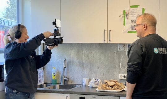 Stine i Yrkesnorsk filmer lederen på dekksenteret der han skjærer opp ferskt brød før lunsj.